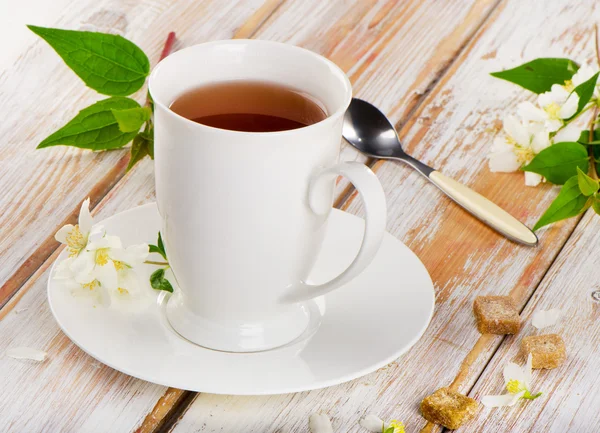 Tee in einer weißen Tasse mit Blumen — Stockfoto