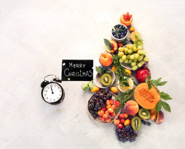 Açık gri arka planda meyvelerden yapılmış Noel ağacı. Yeni yıl tatili konsepti. Üst görünüm, düz görünüm, kopyalama alanı