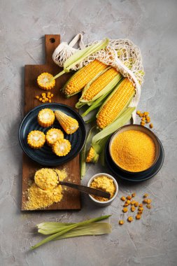 Mısır koçanları ve mısır homurdanmaları gri arka planda. Yemek konseptini hasat et. Üst görünüm, düz görünüm, kopyalama alanı