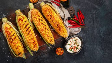 Koyu arkaplanda peynirli ızgara mısır koçanı. Yemek konseptini hasat et. Üst görünüm, düz görünüm, kopyalama alanı