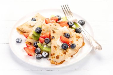 Böğürtlenli krep ve beyaz ahşap arka planda krema. Ev yapımı gıda konsepti. 