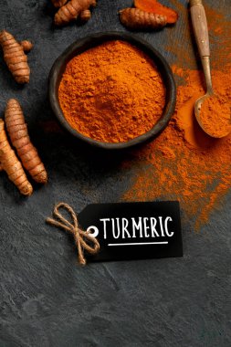 Kase, kaşık ve koyu grunge masasında taze zerdeçal kökleri.