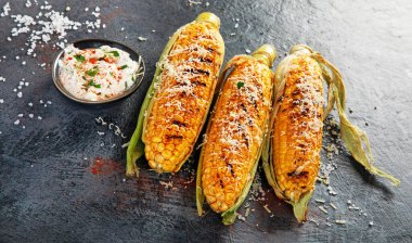 Koyu arkaplanda peynirli ızgara mısır koçanı. Yiyecek konseptini hasat et. 