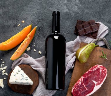 Gri arka planda aperatifleri olan kırmızı şarap. Geleneksel alkol içecekleri. Üst manzara, düz uzanma