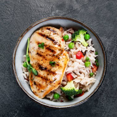 Sebzeli ızgara tavuk ve gri arka planda pilav. Sağlıklı beslenme konsepti. Üst görünüm, düz görünüm, kopyalama alanı