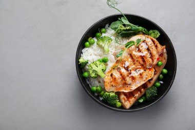 Yeşil sebzeli ızgara tavuk ve gri arka planda pirinç. Sağlıklı beslenme konsepti. Üst görünüm, düz görünüm, kopyalama alanı