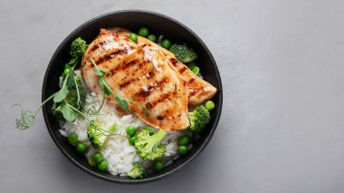 Yeşil sebzeli ızgara tavuk ve gri arka planda pirinç. Sağlıklı beslenme konsepti. Üst görünüm, düz görünüm, kopyalama alanı