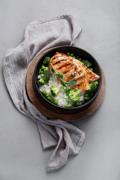 Yeşil sebzeli ızgara tavuk ve gri arka planda pirinç. Sağlıklı beslenme konsepti. Üst görünüm, düz görünüm, kopyalama alanı