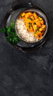 Hint tereyağlı körili tavuk ve koyu arkaplanda basmati pilavı. Geleneksel ev yapımı yemek konsepti. Üst görünüm, alanı kopyala