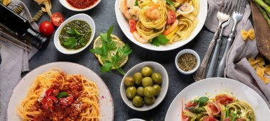 Esmer arka planda makarna çeşitleri. Geleneksel İtalyan yemeği konsepti. Üst manzara, düz uzanma