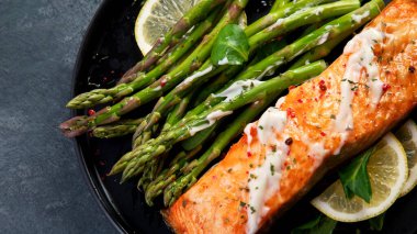 Gri arka planda kuşkonmaz ile pişirilmiş somon balığı. Akdeniz diyeti konsepti. Düz konum, üst görünüm, kopyalama alanı