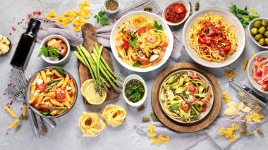 Gri arka planda makarna çeşitleri. Geleneksel İtalyan yemeği konsepti. Üst manzara, düz uzanma