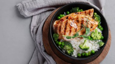 Yeşil sebzeli ızgara tavuk ve gri arka planda pirinç. Sağlıklı beslenme konsepti. Üst görünüm, düz görünüm, kopyalama alanı