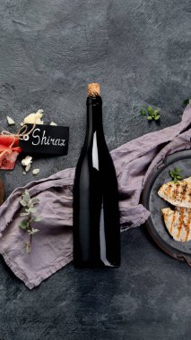 Kırmızı şarap Sirah, gri arka planda aperatifler. Geleneksel alkol içecekleri. Üst görünüm, düz görünüm, kopyalama alanı