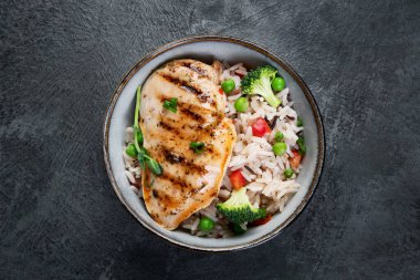 Sebzeli ızgara tavuk ve gri arka planda pilav. Sağlıklı beslenme konsepti. Üst görünüm, düz görünüm, kopyalama alanı