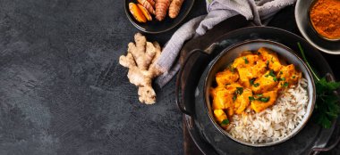 Hint tereyağlı körili tavuk ve koyu arkaplanda basmati pilavı. Geleneksel ev yapımı yemek konsepti. Üst görünüm, kopyalama alanı, panorama