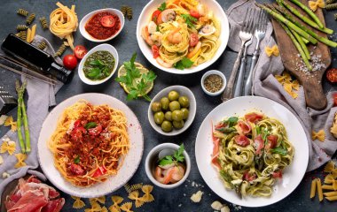 Esmer arka planda makarna çeşitleri. Geleneksel İtalyan yemeği konsepti. Üst manzara, düz uzanma