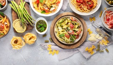 Gri arka planda makarna çeşitleri. Geleneksel İtalyan yemeği konsepti. Üst görünüm, düz görünüm, kopyalama alanı