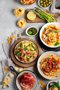 Gri arka planda makarna çeşitleri. Geleneksel İtalyan yemeği konsepti. Üst görünüm, düz görünüm, kopyalama alanı