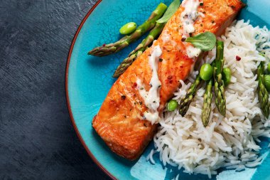 Gri arka planda pilav ve kuşkonmaz ile pişirilmiş somon. Akdeniz diyeti konsepti. Düz konum, üst görünüm, kopyalama alanı