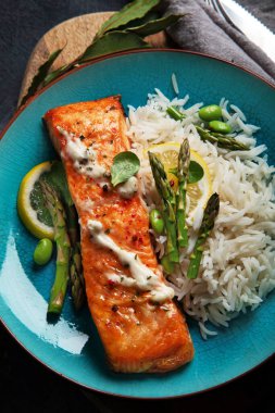 Gri arka planda pilav ve kuşkonmaz ile pişirilmiş somon. Akdeniz diyeti konsepti. Düz yatış, üst görünüm