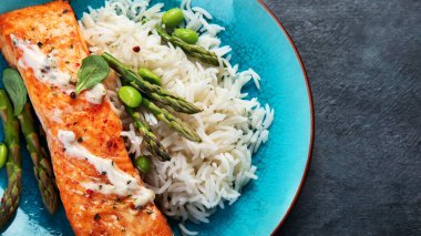 Gri arka planda pilav ve kuşkonmaz ile pişirilmiş somon. Akdeniz diyeti konsepti. Düz konum, üst görünüm, kopyalama alanı