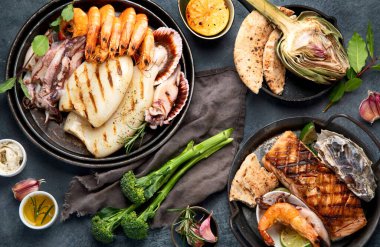 Koyu arka planda ızgara balık ve deniz ürünleri çeşitleri. Ev yapımı yemek konsepti. Üst manzara, düz uzanma