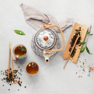 Hafif arka planda bitki çayı olan Asya çaydanlığı. Bitki yaprakları, doğal bitki çayı kompozisyonu. Üst manzara, düz uzanma