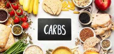 İyi karbonhidrat kaynaklarının seçimi - sebzeler, meyveler, tahıllar, baklagiller, fındıklar ve tohumlar beyaz arka planda, üst görünümde.