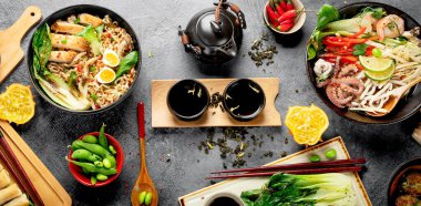 Karanlık arka planda çeşitli malzemeli Asya yemekleri. Üst görünüm.