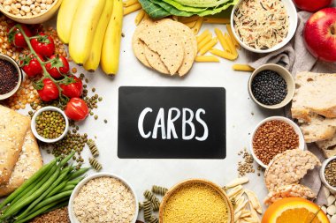 İyi karbonhidrat kaynaklarının seçimi - sebzeler, meyveler, tahıllar, baklagiller, fındıklar ve tohumlar beyaz arka planda, üst görünümde.