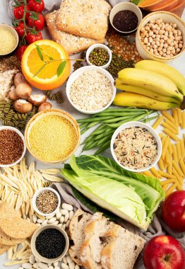 İyi karbonhidrat kaynaklarının seçimi - sebzeler, meyveler, tahıllar, baklagiller, fındıklar ve tohumlar beyaz arka planda, üst görünümde.
