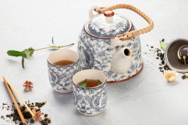 Hafif arka planda bitki çayı olan Asya çaydanlığı. Bitki yaprakları, doğal bitki çayı kompozisyonu. Üst görünüm, düz görünüm, kopyalama alanı