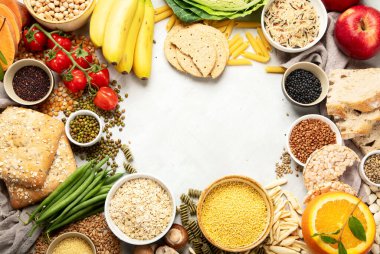 İyi karbonhidrat kaynaklarının seçimi - sebzeler, meyveler, tahıllar, baklagiller, fındıklar ve tohumlar beyaz arka planda, üst görünümde.