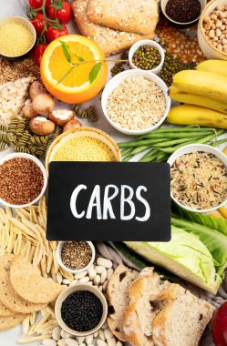 İyi karbonhidrat kaynaklarının seçimi - sebzeler, meyveler, tahıllar, baklagiller, fındıklar ve tohumlar beyaz arka planda, üst görünümde.