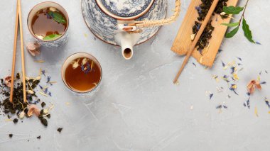 Hafif arka planda bitki çayı olan Asya çaydanlığı. Bitki yaprakları, doğal bitki çayı kompozisyonu. Üst görünüm, düz görünüm, kopyalama alanı