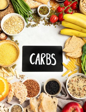 İyi karbonhidrat kaynaklarının seçimi - sebzeler, meyveler, tahıllar, baklagiller, fındıklar ve tohumlar beyaz arka planda, üst görünümde.