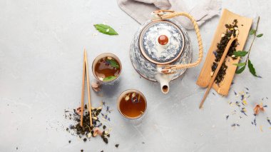 Hafif arka planda bitki çayı olan Asya çaydanlığı. Bitki yaprakları, doğal bitki çayı kompozisyonu. Üst görünüm, düz görünüm, kopyalama alanı