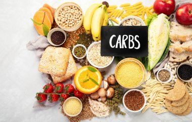 İyi karbonhidrat kaynaklarının seçimi - sebzeler, meyveler, tahıllar, baklagiller, fındıklar ve tohumlar beyaz arka planda, üst görünümde.