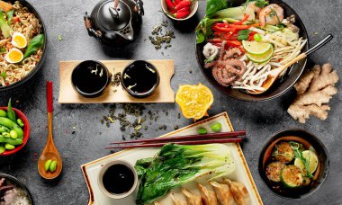 Karanlık arka planda çeşitli malzemeli Asya yemekleri. Üst görünüm.