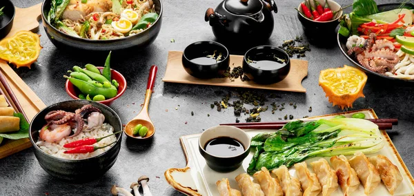 Karanlık arka planda çeşitli malzemeli Asya yemekleri. Panorama.