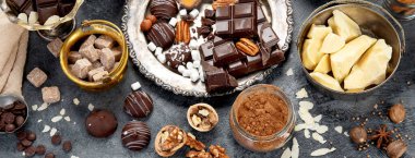 Çikolata, ezilmiş çikolata parçaları, kakao çekirdekleri, kakao yağı, fındık, koyu arkaplan manzarası, panorama..