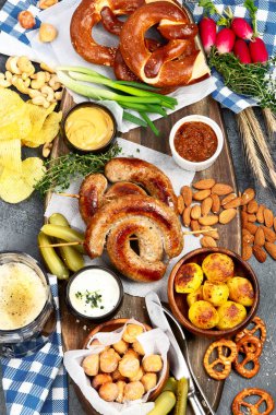 Ekim Festivali yemek masası konsepti ızgara domuz sosisi, kraker, patates, salata, aperatif, sos, koyu arkaplanda bira, üst görünüm..