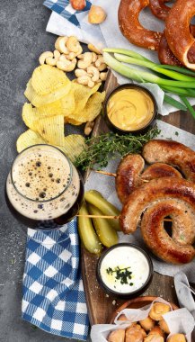 Ekim Festivali yemek masası konsepti ızgara domuz sosisi, kraker, patates, salata, aperatif, sos, koyu arkaplanda bira, üst görünüm..