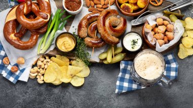 Ekim Festivali yemek masası konsepti ızgara domuz sosisi, kraker, patates, salata, aperatif, sos, koyu arkaplanda bira, üst görünüm..