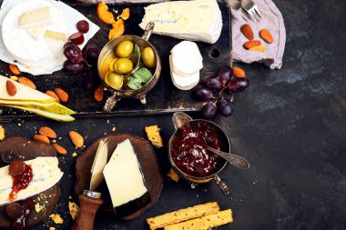 Koyu arkaplanda peynir tahtası. Kutlama toplantısı. Şarap, atıştırmalık, şarküteri. Üst görünüm, düz görünüm, kopyalama alanı