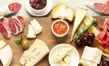 Hafif arka planda peynir çeşitleri. Gurme aperatifleri tepside. İtalyan yemeği konsepti. Üst manzara, düz uzanma