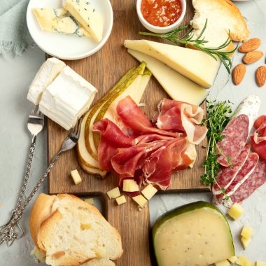 Hafif arka planda peynir çeşitleri. Gurme aperatifleri tepside. İtalyan yemeği konsepti. Üst manzara, düz uzanma