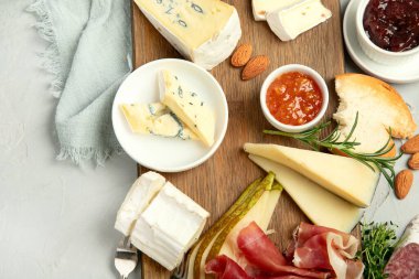 Hafif arka planda peynir çeşitleri. Gurme aperatifleri tepside. İtalyan yemeği konsepti. Üst görünüm, düz görünüm, kopyalama alanı