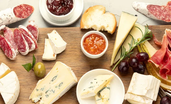 Hafif arka planda peynir çeşitleri. Gurme aperatifleri tepside. İtalyan yemeği konsepti. Üst manzara, düz uzanma